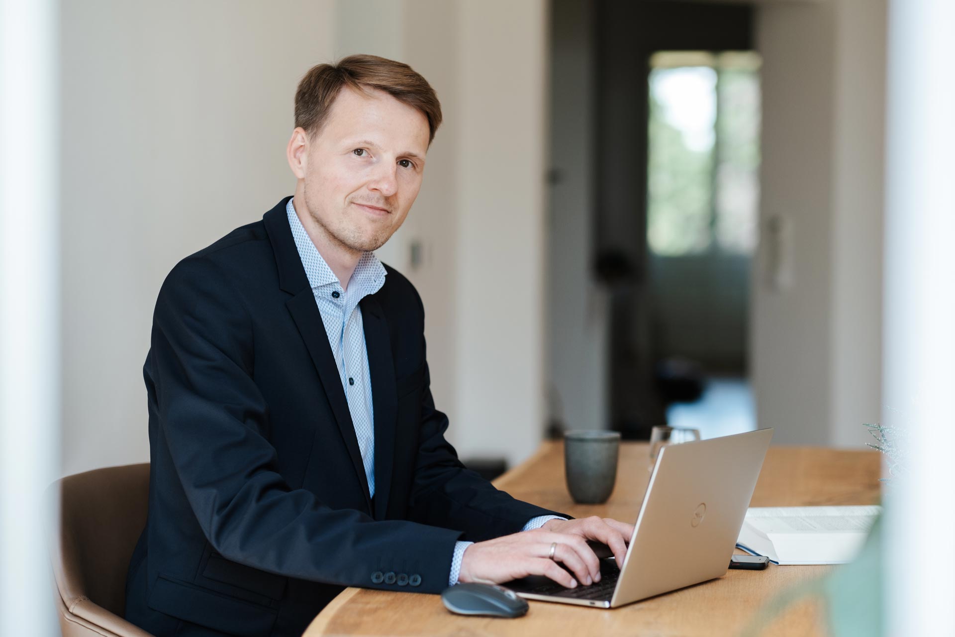 Dennis Quas, IT-Berater aus Bremen, sitzt am Schreibtisch und tippt auf dem Notebook – schaut in die Kamera.