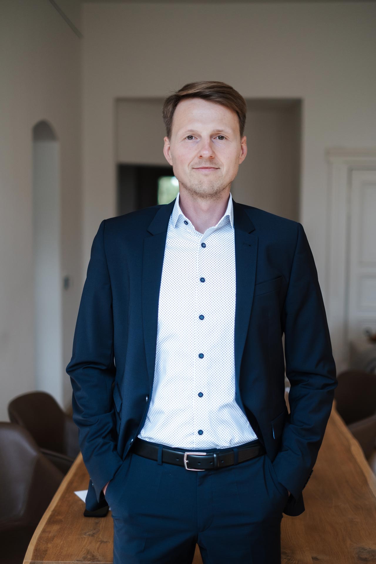 Porträt vom IT-Professional Dennis Quas. Er steht vor einem Besprechungstisch.